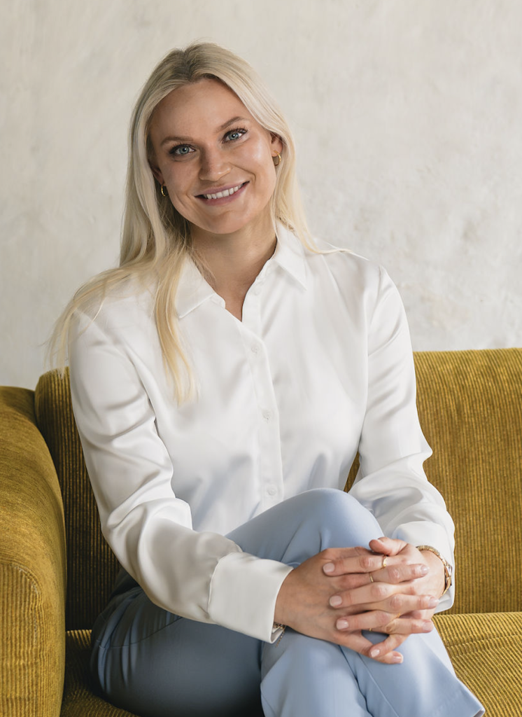 Psykolog Danielle Dahlhus – ekspert i behandling af søvnangst – sidder smilende på sofa. Illustration af tryghed og professionel hjælp mod søvnangst.